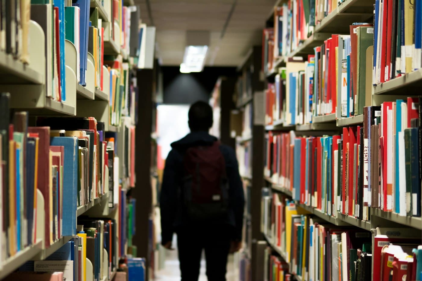 A figure walking between bookshelves at the end of the day.