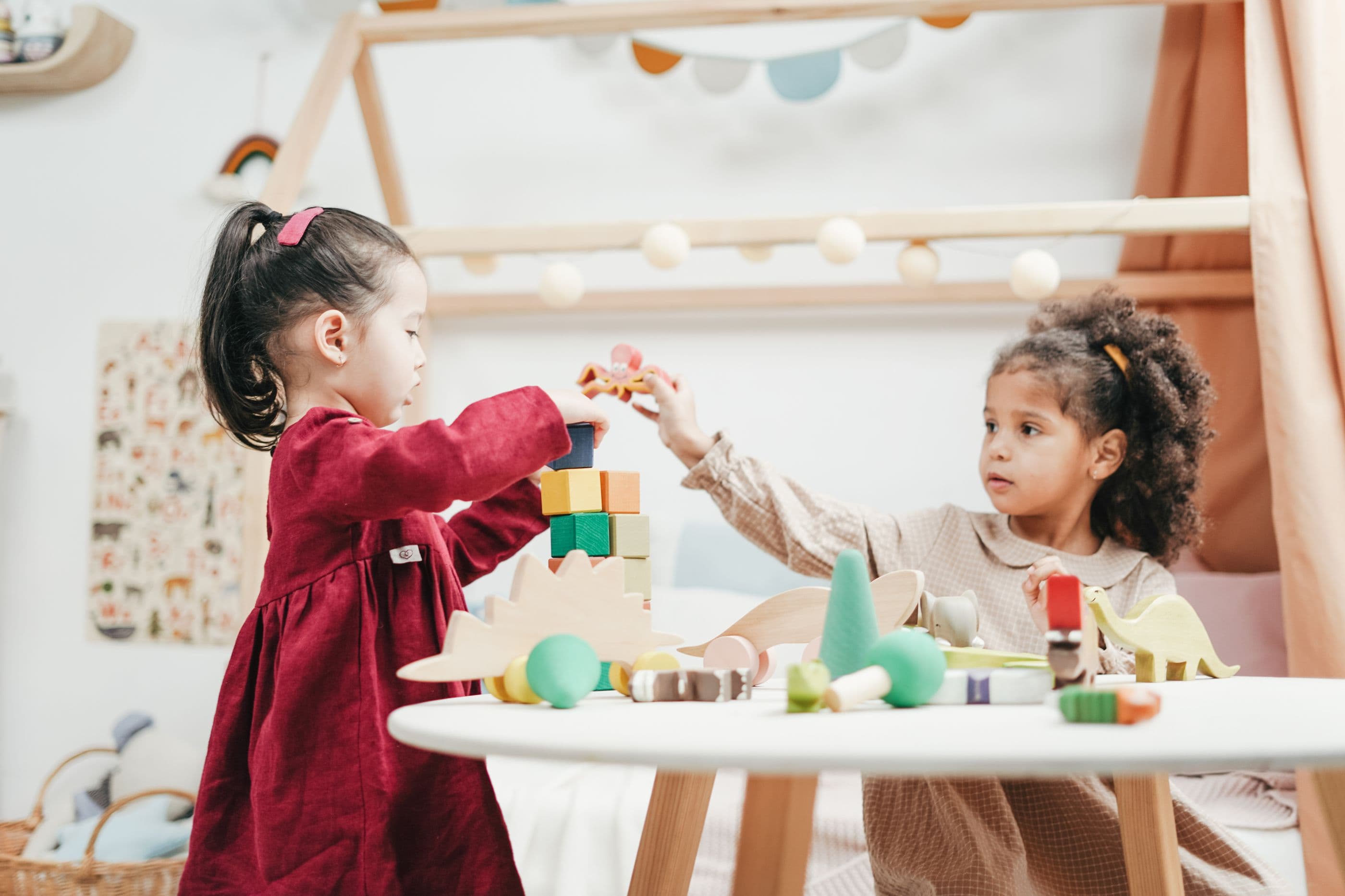 Two children building with wooden blocks, facing the work rather than the camera.